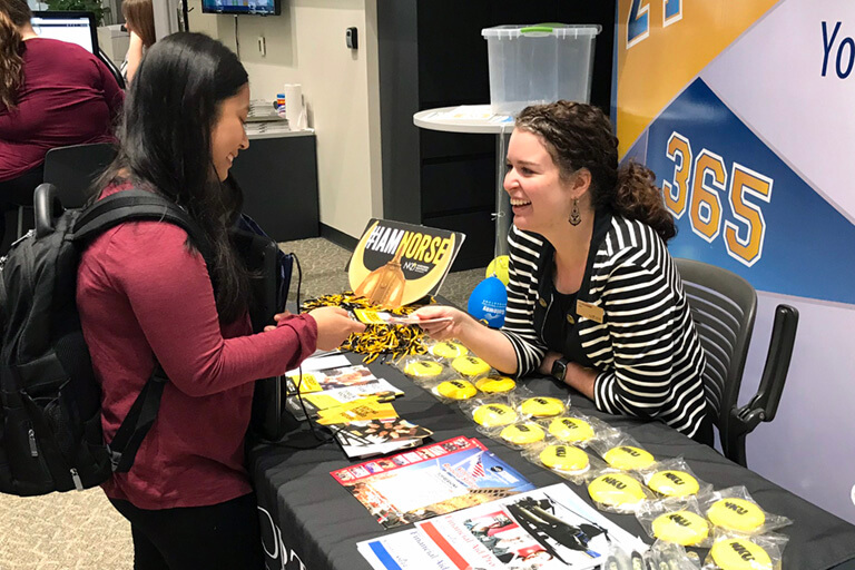 female student stands at NKU recruiters table speaking to representative from NKU. text overlay reads transfer
