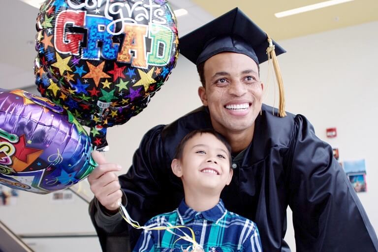 Man in graduation gown posing with a young boy